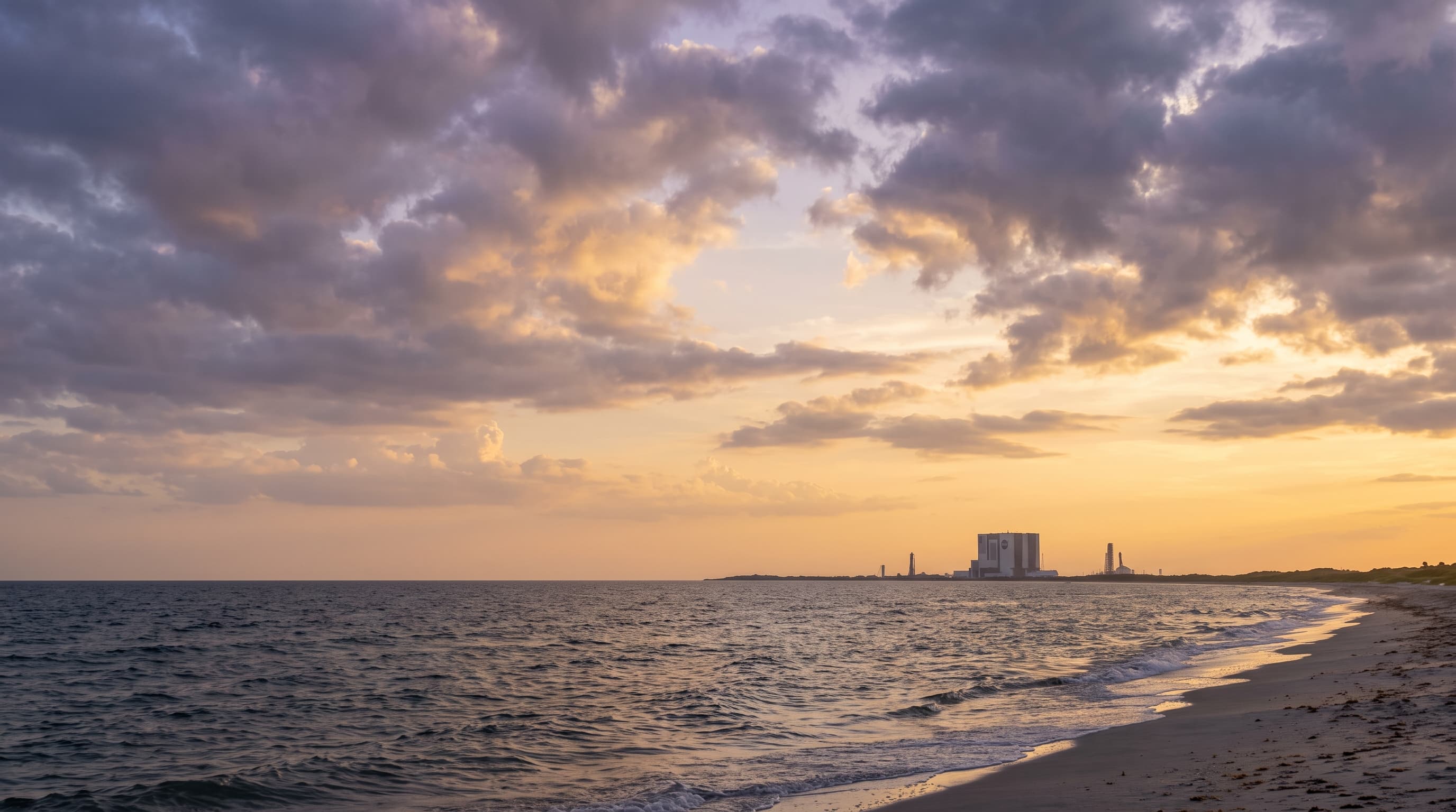 Sunrise breaking over the Atlantic at Florida's Space Coast with parting clouds and a coastal launch-site silhouette